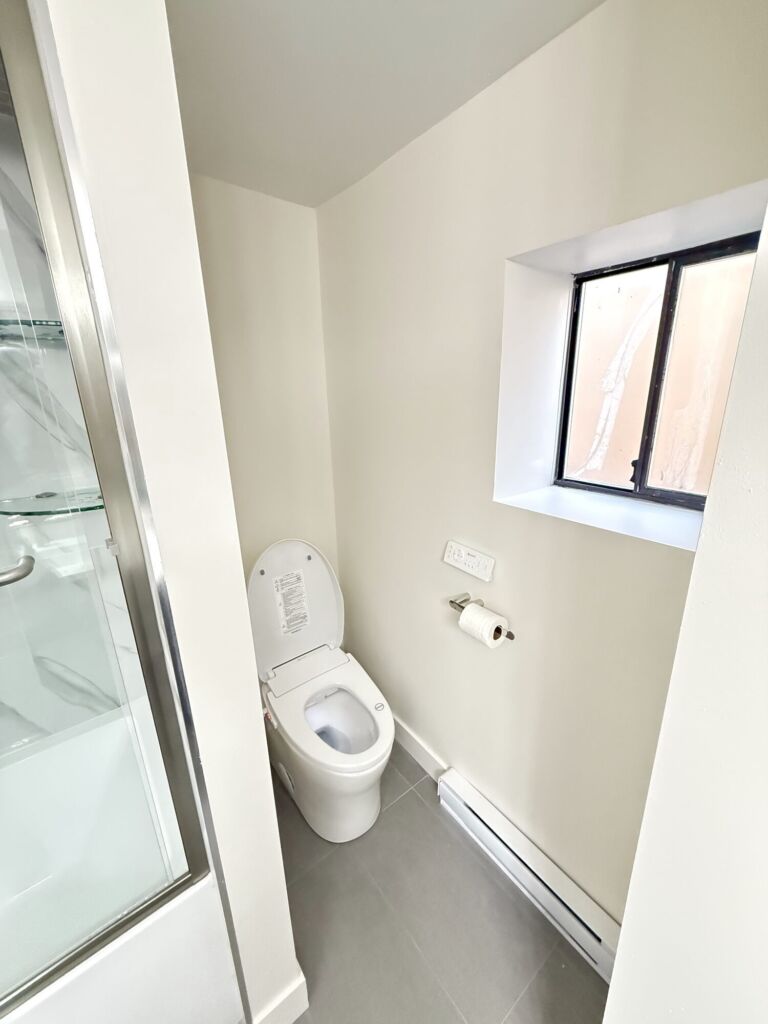 Bathroom renovation with glass shower and wall-hung smart toilet