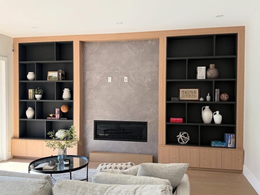 Built-in wood and black shelving around a stone-look fireplace feature wall