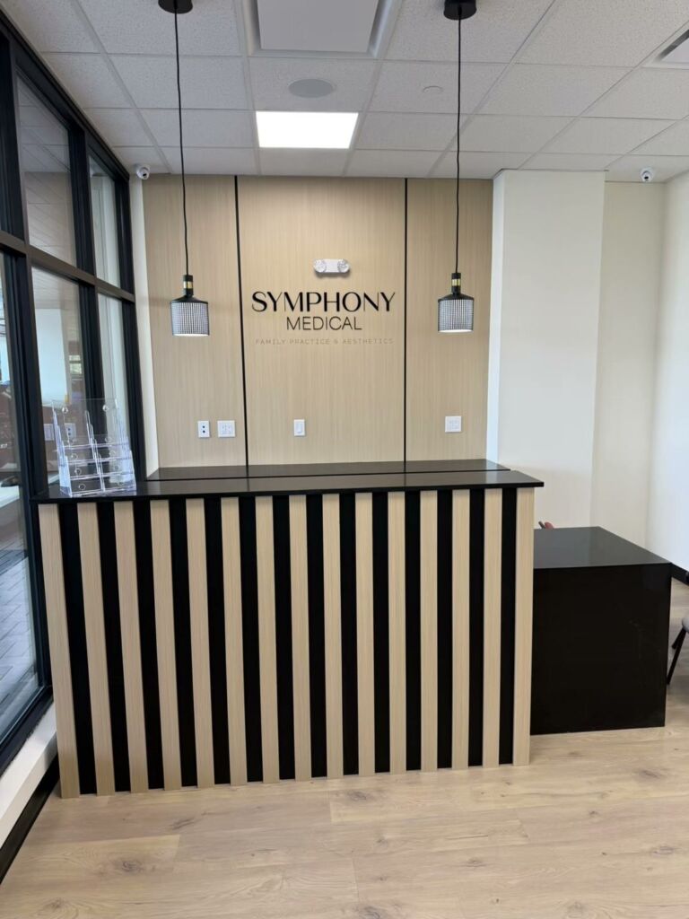 Medical clinic reception desk with slatted front and wood feature wall, commercial interior by RK Modern Construction