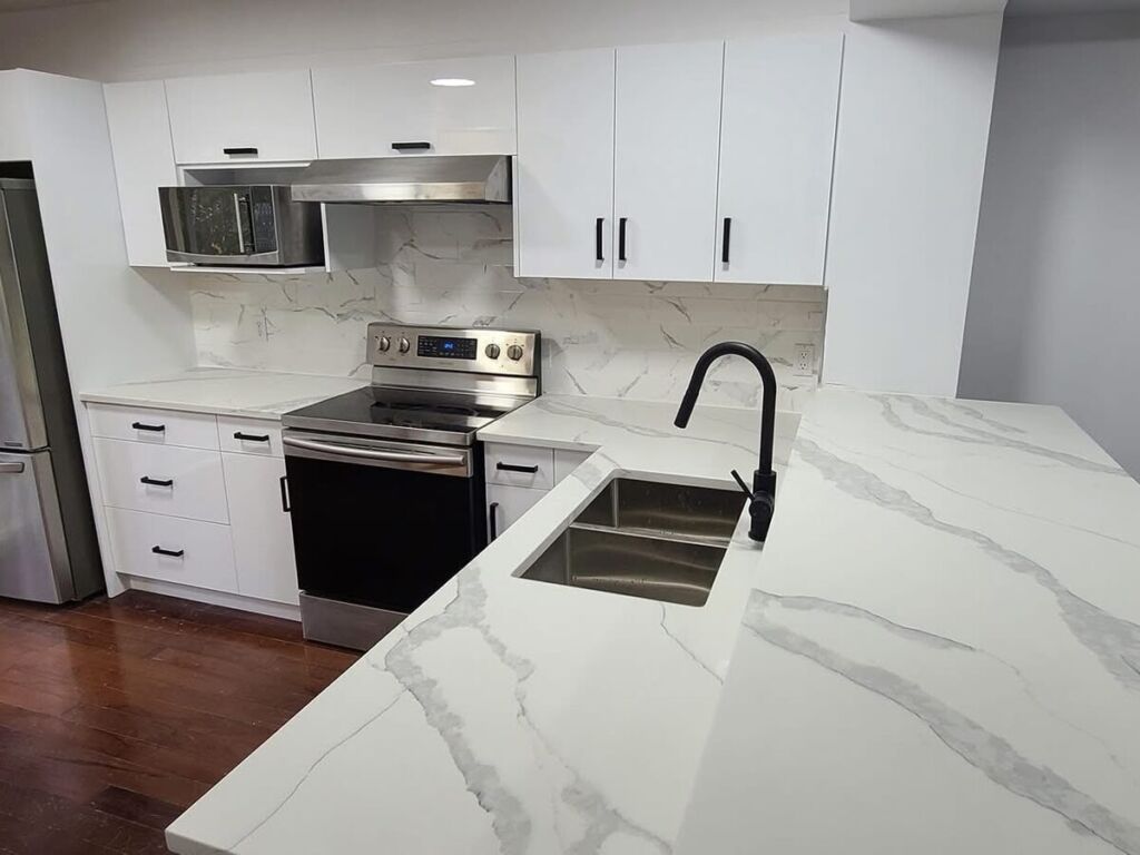 White kitchen with quartz waterfall peninsula and black faucet