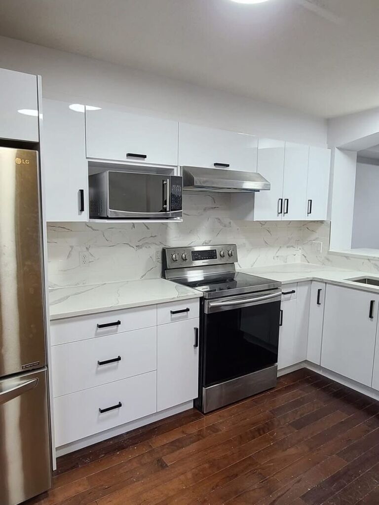 White kitchen renovation with marble-look backsplash and stainless appliances